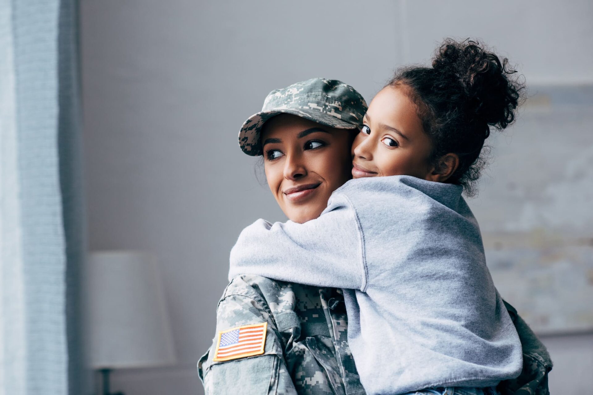 military woman hugging a little girl